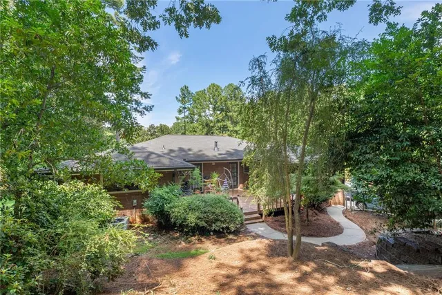 a view of a back yard with plants and a bench