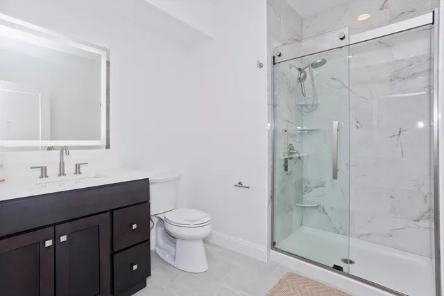 a bathroom with a shower sink vanity mirror and toilet