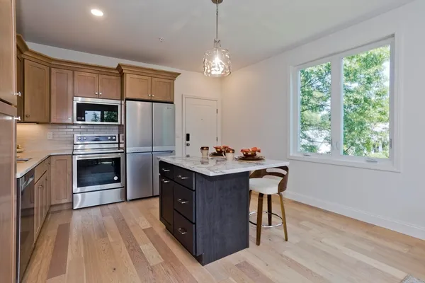 a kitchen with kitchen island granite countertop a stove oven and a refrigerator with cabinets