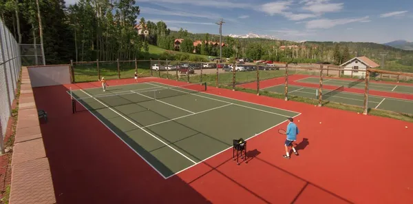 a view of a tennis ground with large trees