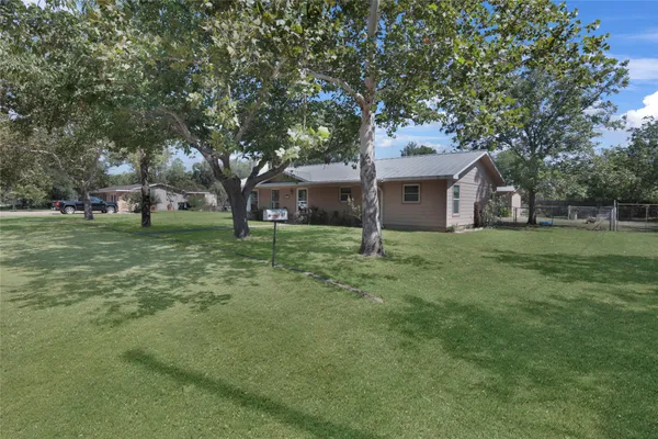 a house that is sitting in the grass with tress in the background