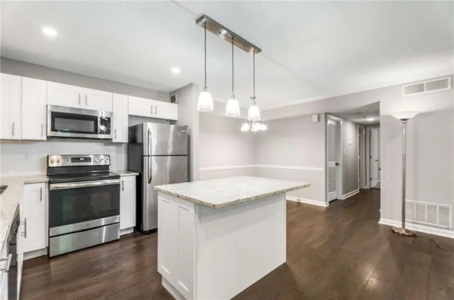 a kitchen with kitchen island white cabinets and stainless steel appliances