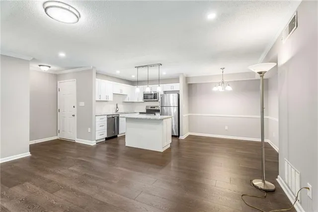 a kitchen with stainless steel appliances kitchen island granite countertop a refrigerator oven a sink with a dining table and chairs