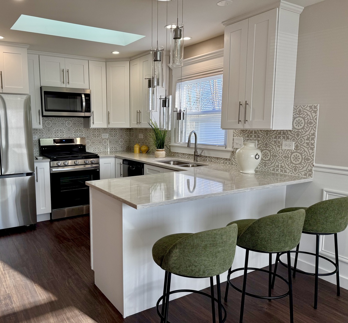 11657 South Racine Avenue Chicago, IL 60643 - Photo 4 of 40 a kitchen with stainless steel appliances granite countertop a stove a sink a microwave a dining table and chairs with wooden floor