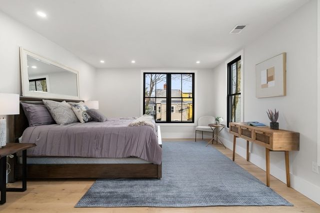 a spacious bedroom with a bed a table and windows