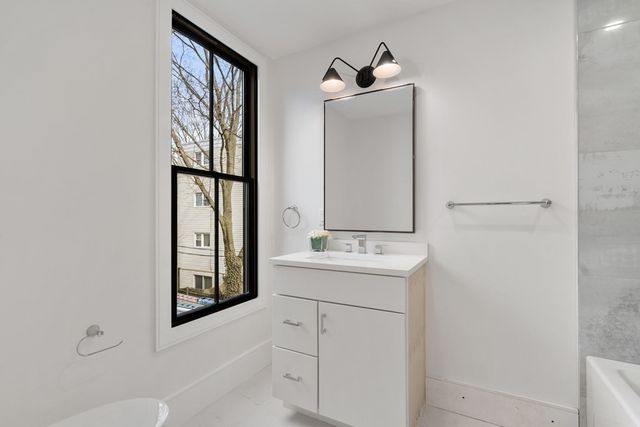 a bathroom with a bathtub sink vanity and mirror