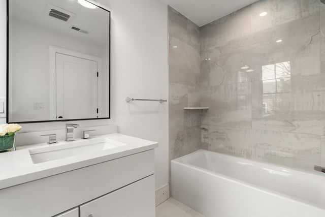 a bathroom with a bathtub shower sink vanity and toilet