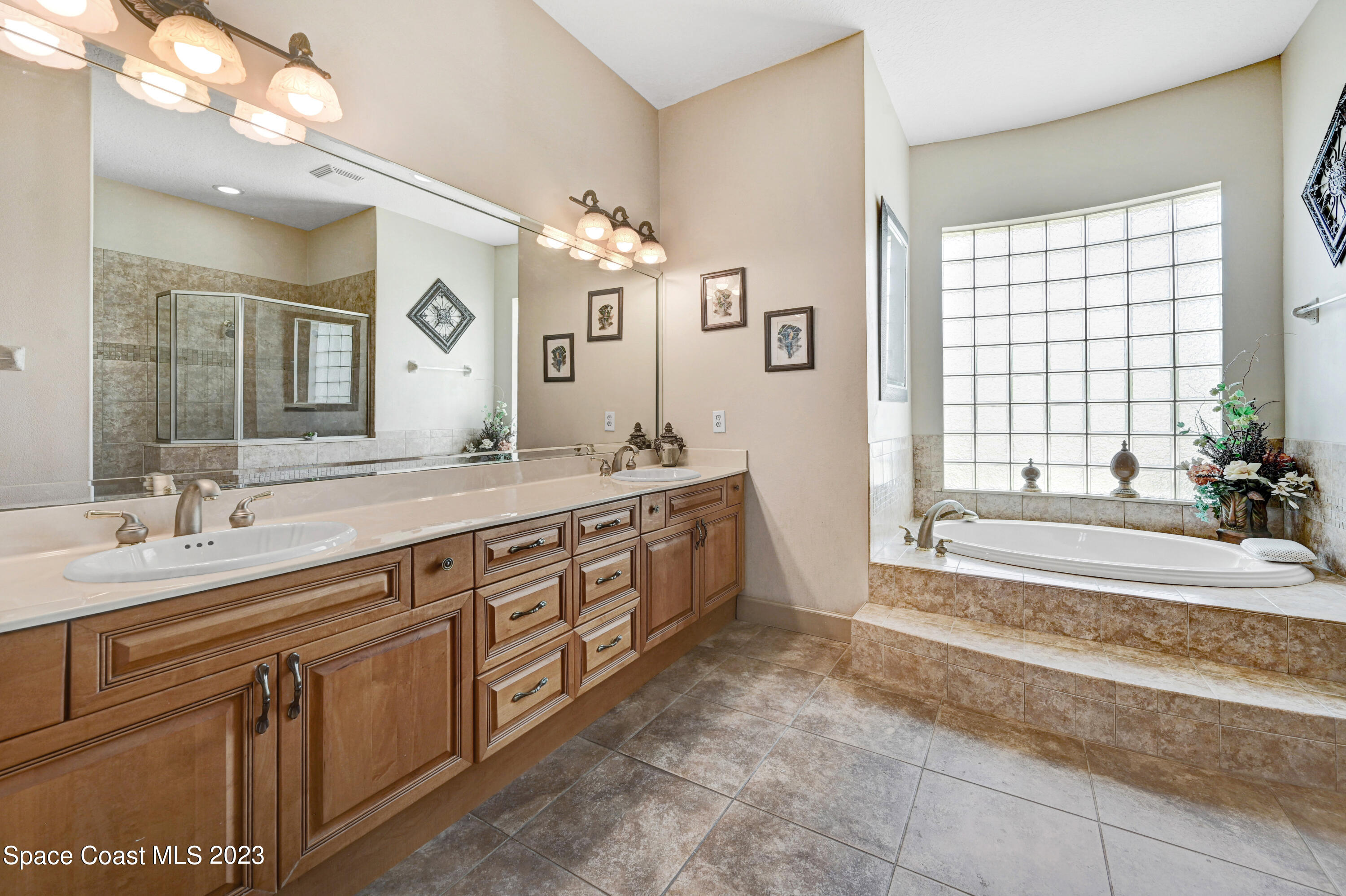 1317 Centennial Way Rockledge, FL 32955 - Photo 23 of 38 a spacious bathroom with a double vanity sink a large mirror and a bathtub