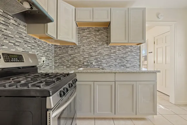 a kitchen with granite countertop a stove sink and cabinets