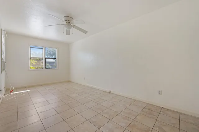 an empty room with windows and fan