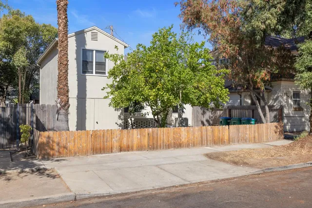 a view of a house with a small yard and wooden fence