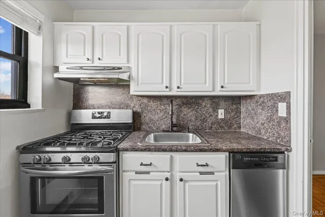 a kitchen with granite countertop a stove sink and cabinets