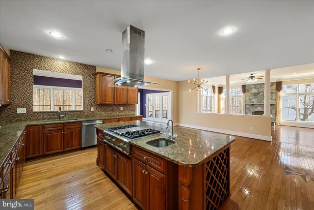 a kitchen with stainless steel appliances granite countertop a stove a sink dishwasher and a refrigerator with wooden cabinets