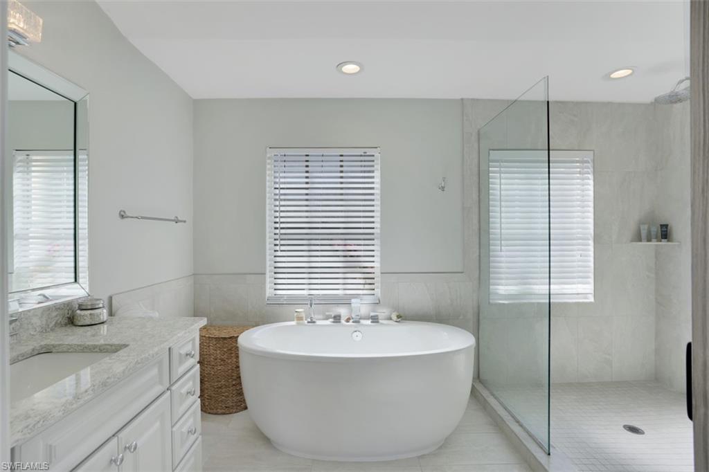 7311 Mill Pond Circle Naples, FL 34109 - Photo 14 of 22 a bathroom with a granite countertop sink and a bathtub