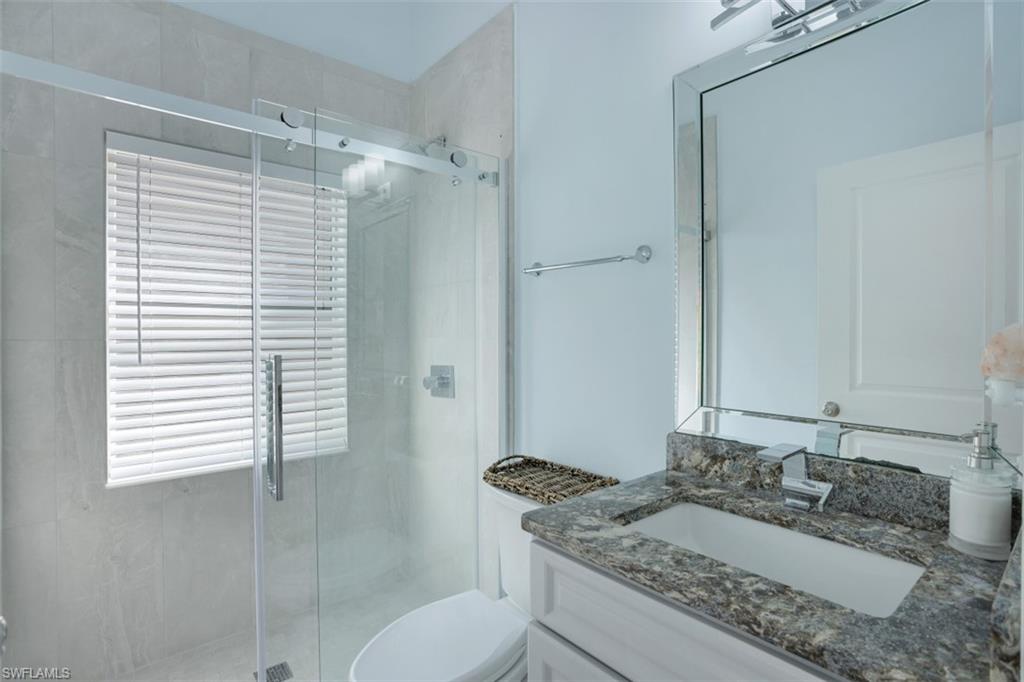 7311 Mill Pond Circle Naples, FL 34109 - Photo 17 of 22 a bathroom with a granite countertop sink toilet and shower