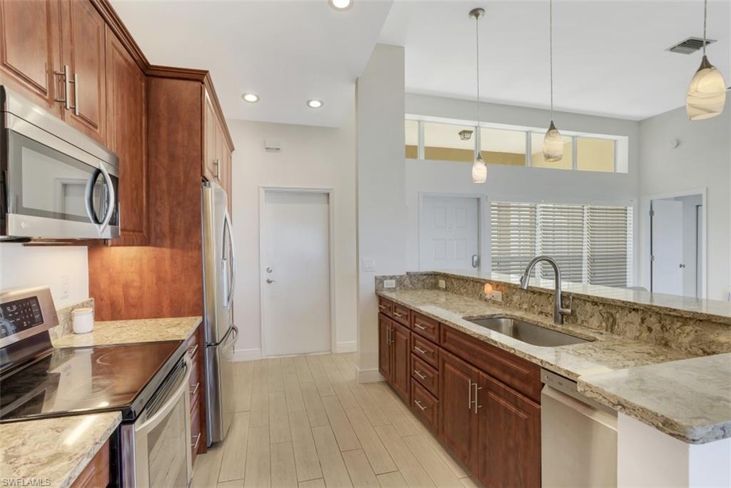 7311 Mill Pond Circle Naples, FL 34109 - Photo 2 of 22 a kitchen with stainless steel appliances granite countertop a sink stove and refrigerator