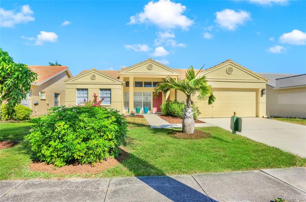 7311 Mill Pond Circle Naples, FL 34109 - Photo 22 of 22 a front view of a house with a garden and yard