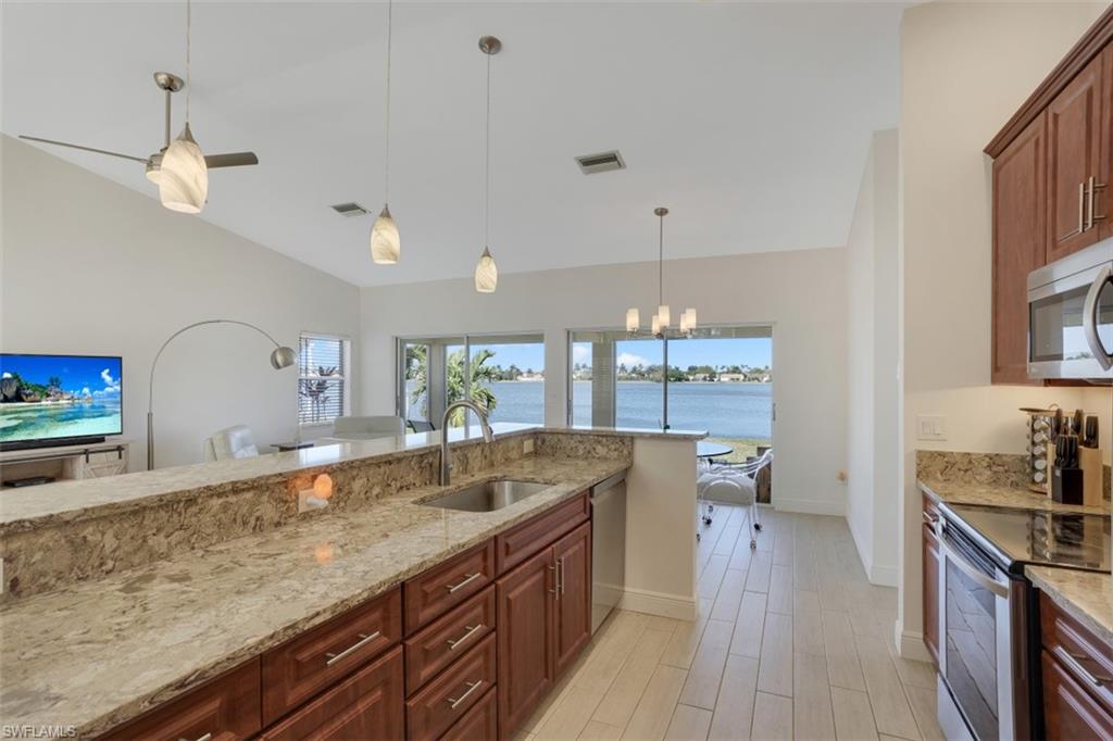 7311 Mill Pond Circle Naples, FL 34109 - Photo 3 of 22 a spacious kitchen with stainless steel appliances granite countertop a sink a stove counter space and cabinets