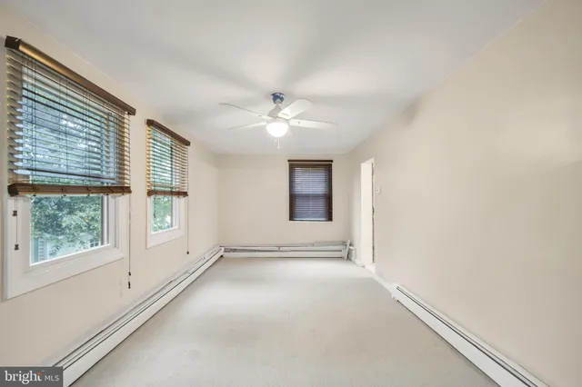 an empty room with windows and chandelier fan