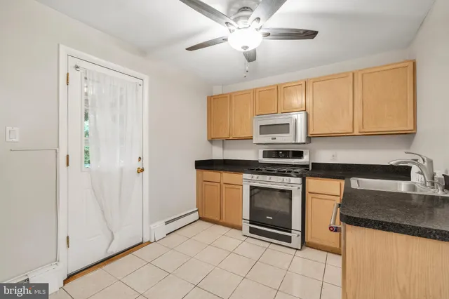 a kitchen with granite countertop a sink stainless steel appliances and white cabinets