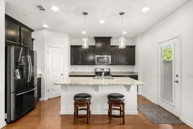 a kitchen with refrigerator a sink and chairs