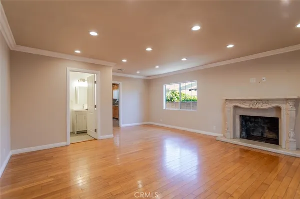 a view of an empty room with wooden floor fireplace and a window