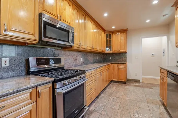 a kitchen with stainless steel appliances granite countertop a stove top oven a sink dishwasher and a microwave oven on the granite countertops