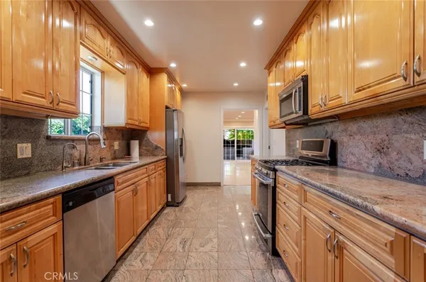 a kitchen with stainless steel appliances granite countertop a stove a sink and a microwave
