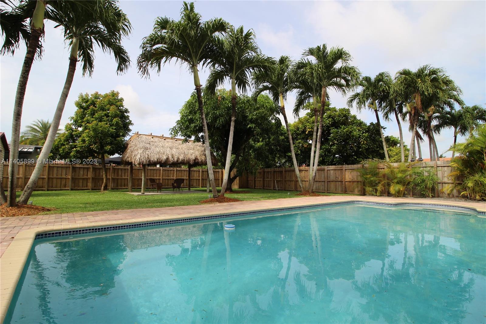 10810 Southwest 28th Street Miami, FL 33165 - Photo 7 of 45 a view of a swimming pool with a yard and palm trees