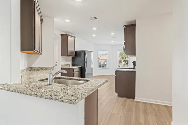 a kitchen with stainless steel appliances granite countertop a refrigerator a stove top oven a sink and dishwasher