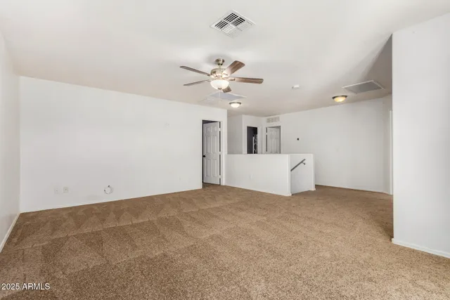 a view of a big room with a chandelier fan and windows