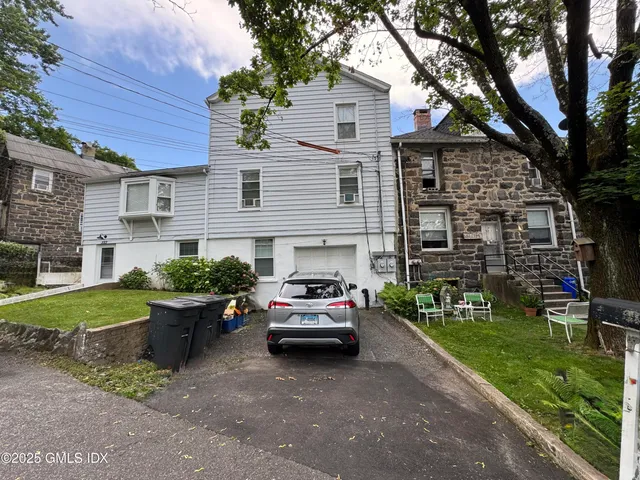 a front view of a house with a garden and trees