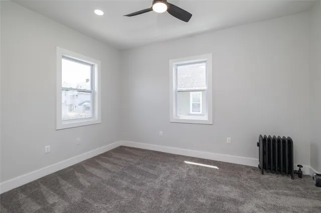 an empty room with ceiling fan and windows