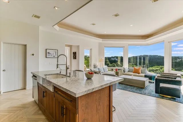 a living room with stainless steel appliances granite countertop a sink and a large window