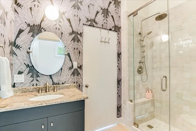a bathroom with a granite countertop sink mirror and shower