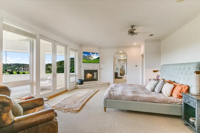 a spacious bedroom with a bed a couch and a large window with the garden view