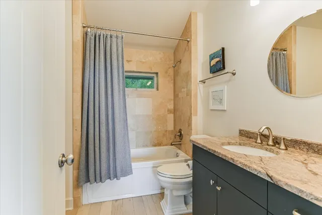 a bathroom with a granite countertop sink toilet and shower