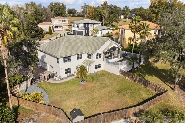 an aerial view of a house with swimming pool and large trees