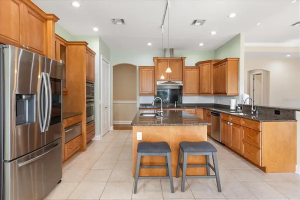 a large kitchen with stainless steel appliances kitchen island granite countertop a refrigerator and a stove top oven