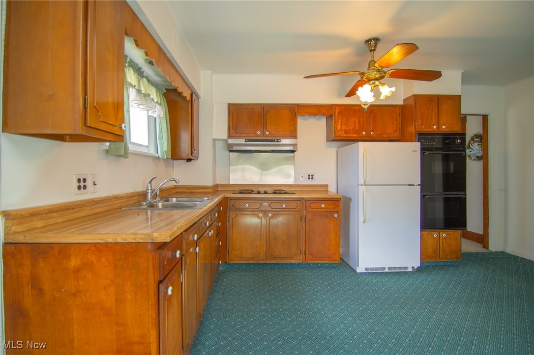 56260 Davis Road Bellaire, OH 43906 - Photo 33 of 44 Kitchen with under cabinet range hood, brown cabinetry, black appliances, and ceiling fan