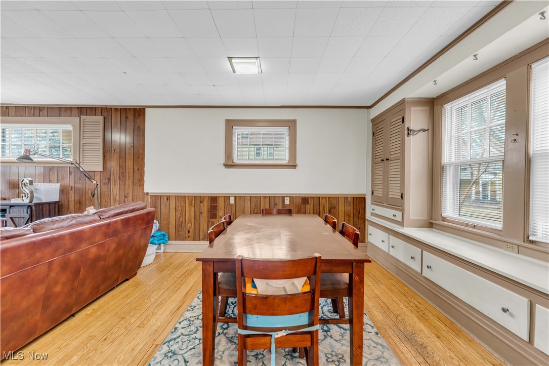 3729 Grosvenor Road Cleveland, OH 44118 - Photo 18 of 39 Dining area featuring light wood-style flooring, a wainscoted wall, wood walls, and ornamental molding