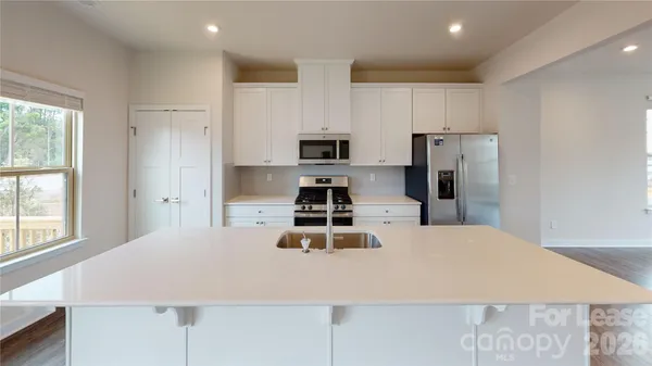 a kitchen with kitchen island a stove a refrigerator and a sink