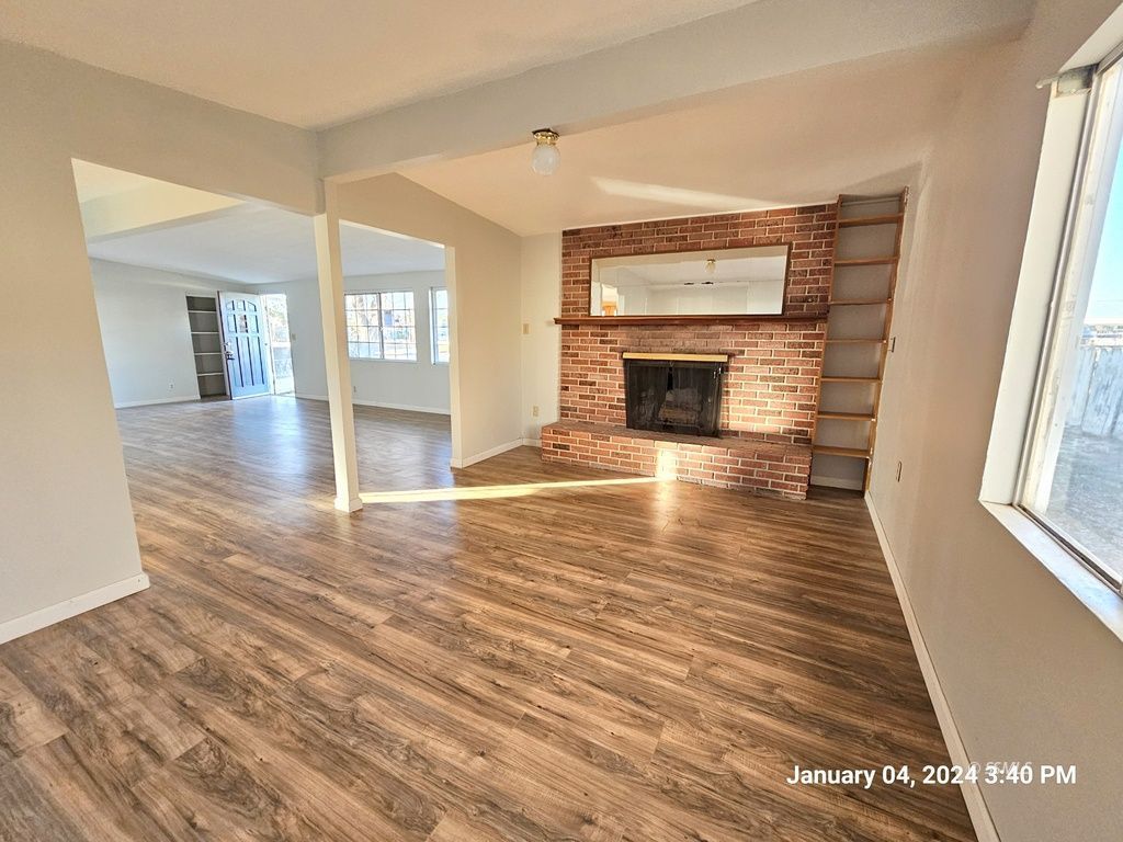 439 West Reeves Avenue Ridgecrest, CA 93555 - Photo 3 of 20 an empty room with wooden floor fireplace and windows