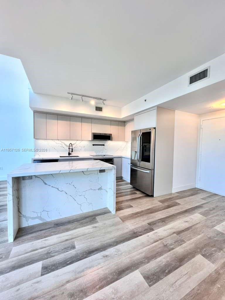 90 Southwest 3rd Street, Unit TH300A Miami, FL 33130 - Photo 5 of 21 a kitchen with stainless steel appliances kitchen island granite countertop a refrigerator and a stove top oven