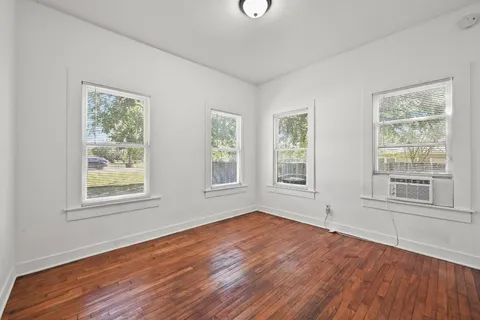 a view of empty room with wooden floor and fan