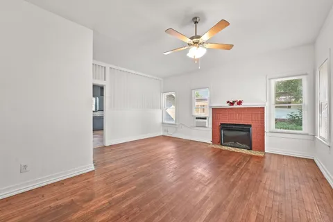 a view of empty room with wooden floor fireplace and a window