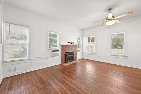 a view of empty room with wooden floor fireplace and fan