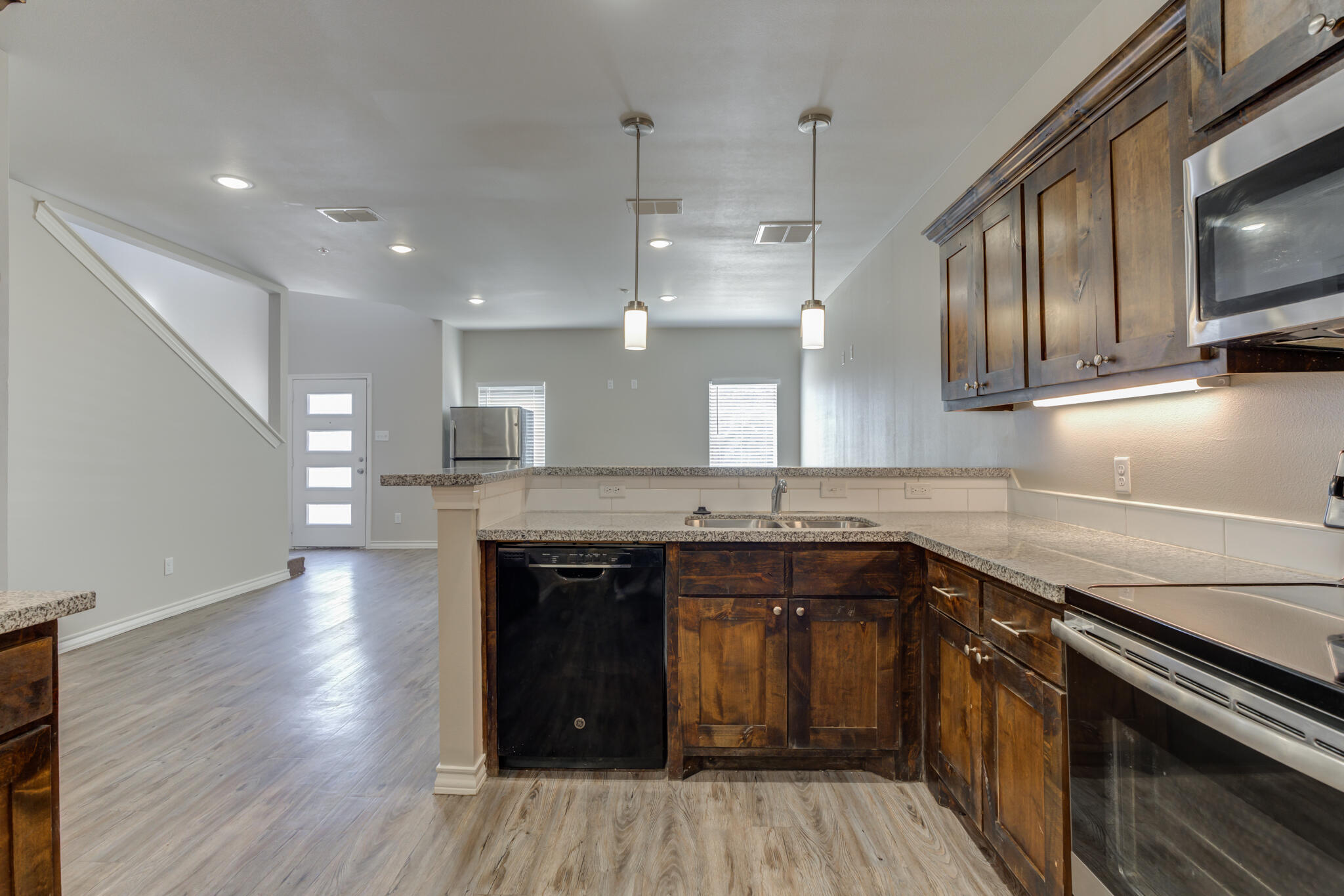 3404 25th Street Lubbock, TX 79410 - Photo 11 of 38 a kitchen with stainless steel appliances granite countertop wooden cabinets a sink dishwasher a stove and a refrigerator with wooden floor