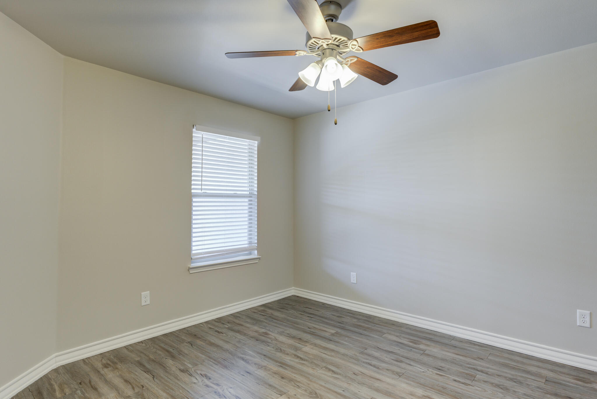 3404 25th Street Lubbock, TX 79410 - Photo 14 of 38 an empty room with wooden floor chandelier fan and windows
