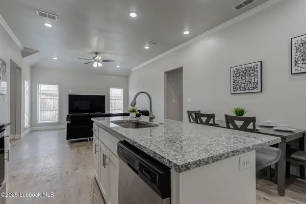 a kitchen with granite countertop kitchen island stainless steel appliances a sink and a refrigerator